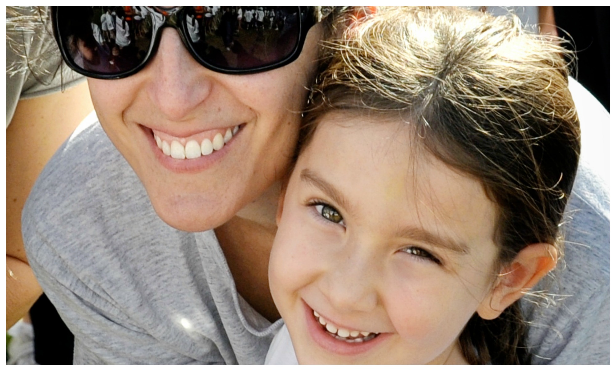 Woman and young girl smiling closely together.